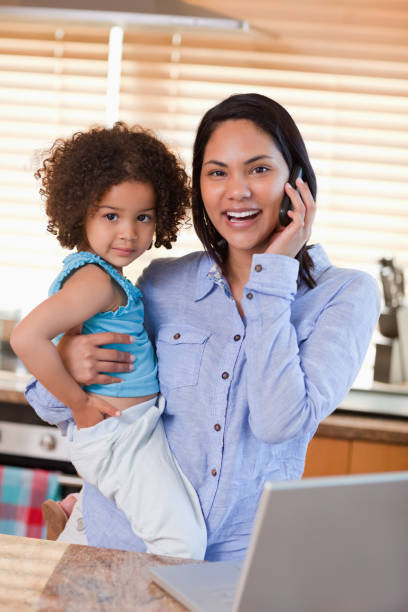 istock Mother and daughter using cellphone in the kitchen together 827962872