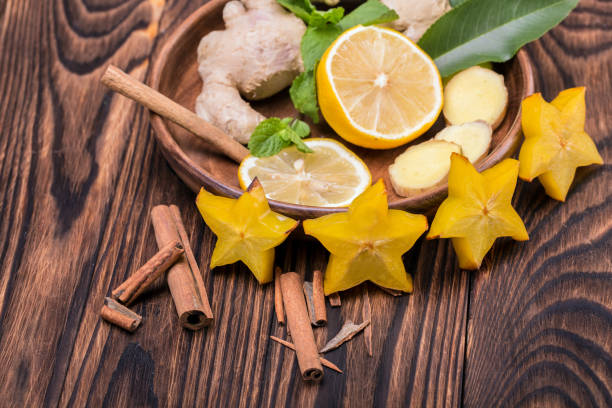 une assiette pleine de carambole jaune, citron aigre et cannelle parfumée sur un fond en bois. ingrédients du thé en bonne santé. - sour taste green traditional culture lemon photos et images de collection