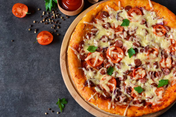 istock Home pizza with salami, tomato and cheese on a black background 827988018