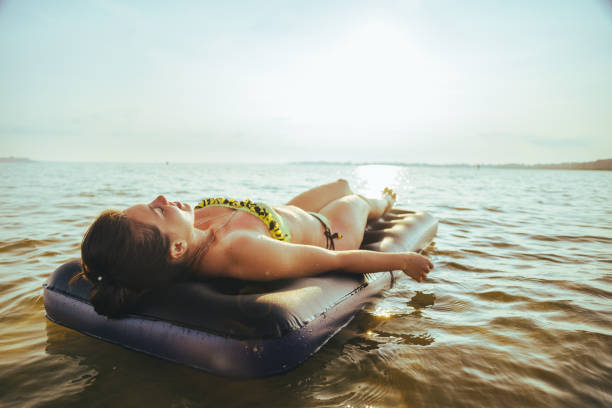istock woman get tan while lying on Inflatable mattress 828004286
