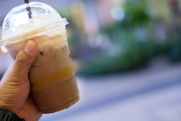 istock Chocolate frappe with whipped cream in plastic glass on young hand 828005234