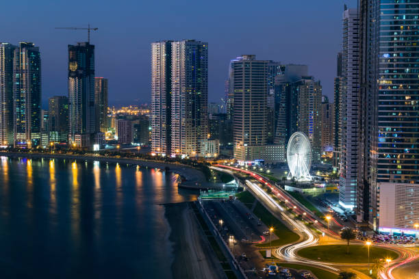 Sharjah, Al Khan Corniche Street Sharjah, Al Khan Lagoon waterfront, with the Al Qasba ferris wheel, illuminated at sunset emirate of sharjah stock pictures, royalty-free photos & images