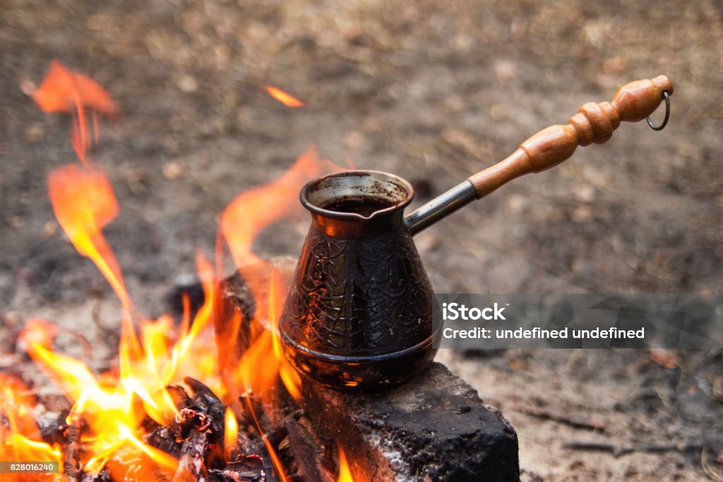 Metal cezve with hot flavored coffee on a bonfire closeup. Adventure Stock Photo