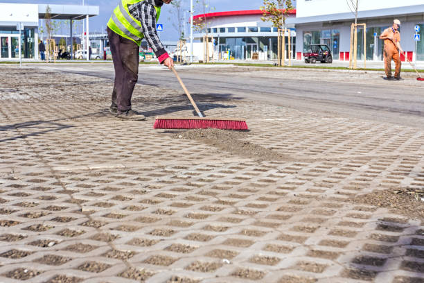 Worker is cleaning new parking place with red broom Zrenjanin, Vojvodina, Serbia – September 10, 2015: Worker sweeps urban space with a wide broom, brush cleaning in the large complex shopping mall "AVIV PARK" in Zrenjanin city. pavement ends sign stock pictures, royalty-free photos & images