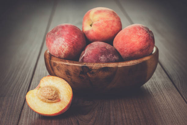 istock wooden bowl with some peaches on the table 828029908