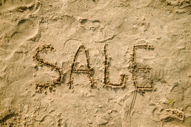 istock sale written in the sand on a beach 828048112