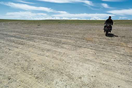 A horse wrangler rides a motocycle in the Gobi Desert in Mongolia.