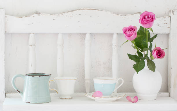 istock pinc roses in vase and dinnerware on white wooden shelf 828082812