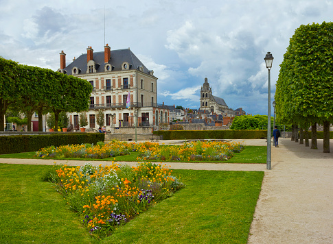Blois, France – May 12, 2017: House of Magician Robert-Houdin (La Maison de la Magie Robert-Houdin), which is a museum, and Blois Cathedral seen across garden with flowers and people