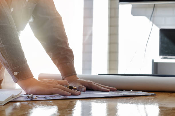 istock Architect holding a pen on project blueprint, architectural concept 828109444