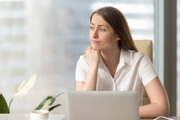 istock Discontented thoughtful woman holding hand under chin bored at workplace 828110556