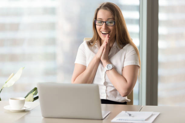 szczęśliwa bizneswoman śmieje się z radości, chętnie patrząc na ekranie laptopa - surprise business happiness women zdjęcia i obrazy z banku zdjęć