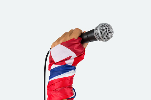 Hand with flag wristband holding microphone,isolated white background.