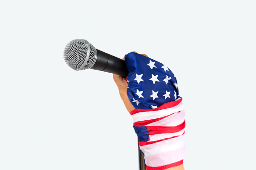 Hand with flag wristband holding microphone,isolated white background.