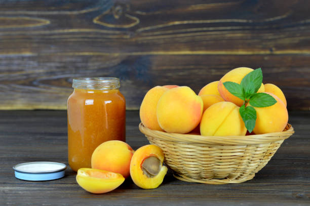 Apricot jam and fresh apricots in the bowl on wooden table