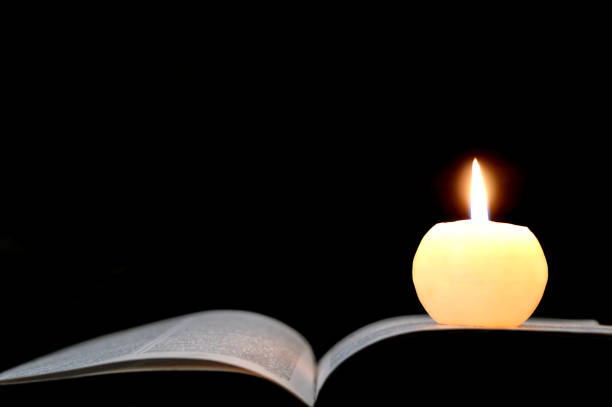 istock Candle and opened book isolated on black background 828137594