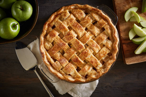 Homemade Apple Pie On A Wood Surface Series of homemade whole and sliced apple pie images on a dark wood surface with ingredients and utensils. apple pie photos stock pictures, royalty-free photos & images