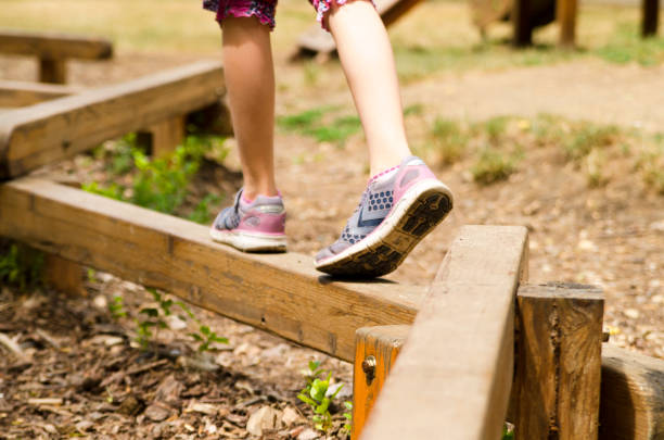 perna de criança jogar equilíbrio na trave de madeira no parque. - balance beam - fotografias e filmes do acervo