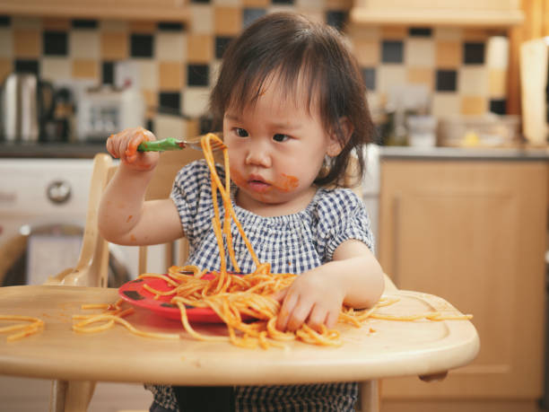 istock baby girl eating messy spaghetti 828175198