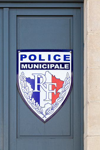 Aizenay, France - July 27 2017: Police Municipale sign fixed on the entrance door of a french police station. It is shaped as a shield with the french flag covering the french map and the initials \