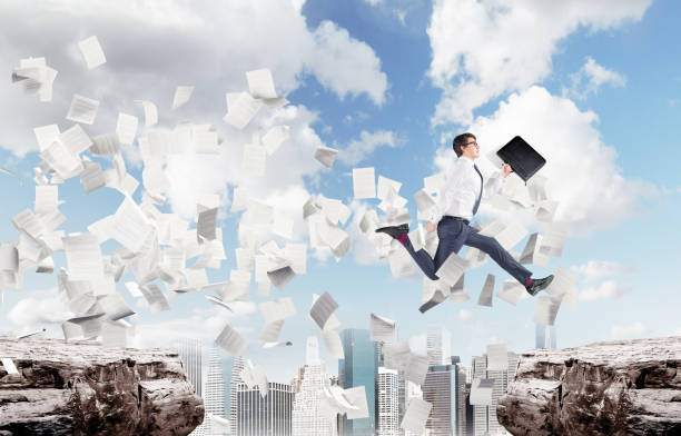 istock Businessman jumping over a chasm in a city, papers 828191340