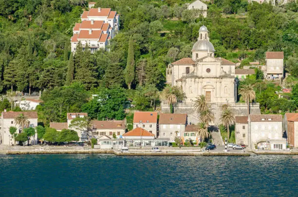 Prcanj.  The town's waterfront with a long line of stone villas and the most impressive feat of architecture in Prcanj - the Birth of Our Lady church, designed by a Venetian architect Bernardino Maccaruzzi. The church has a monumental baroque facade with Corinthian and Doric columns.