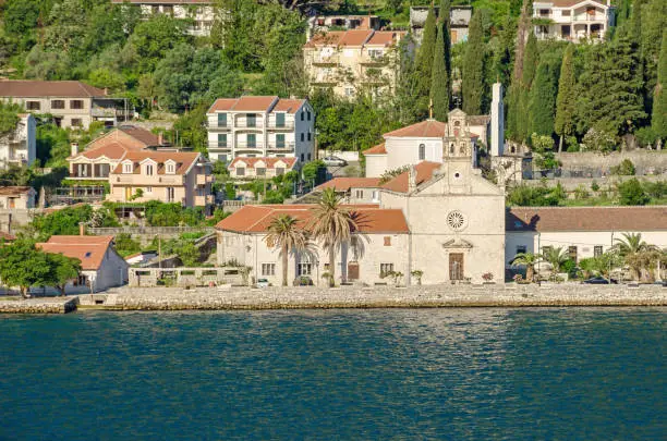 Prcanj - a small town along the Bay of Kotor, Montenegro. A part of the waterfront, that consists of a long line of stone villas and churches, separated by gardens and olive orchards.