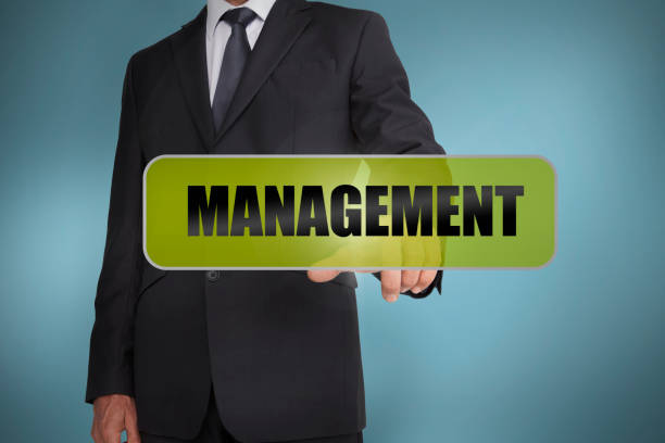 Businessman touching the word management written on green tag Businessman touching the word management written on green tag on blue background management quota feesc stock pictures, royalty-free photos & images