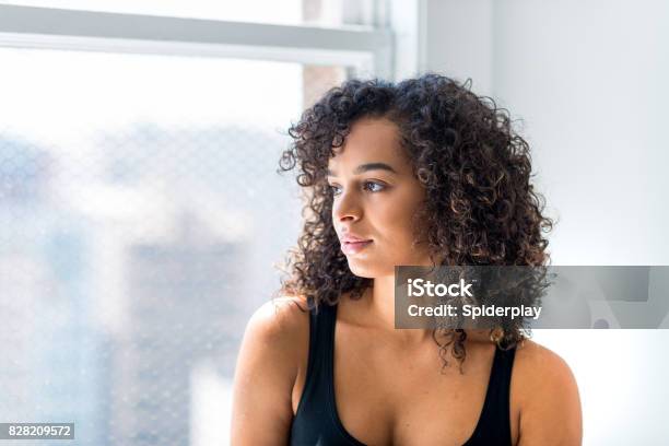 Woman Stares Out Of The Window Of Her Loft Stock Photo - Download Image Now - One Woman Only, Profile View, Latin American and Hispanic Ethnicity