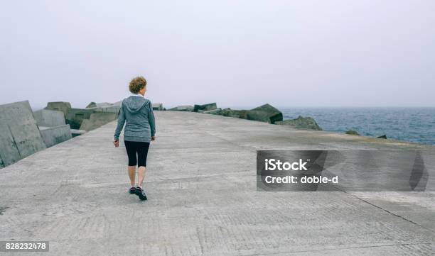 Back View Of Woman Walking By Sea Pier Stock Photo - Download Image Now - Exercising, Girl Power, Relaxation Exercise