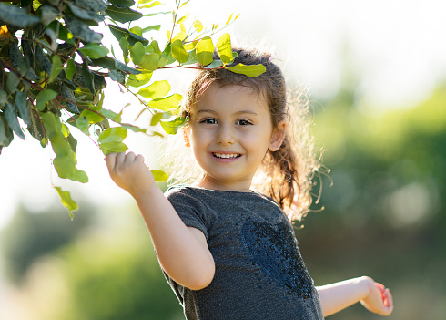 Portrait of smiling girl holding twig at park, selective focus