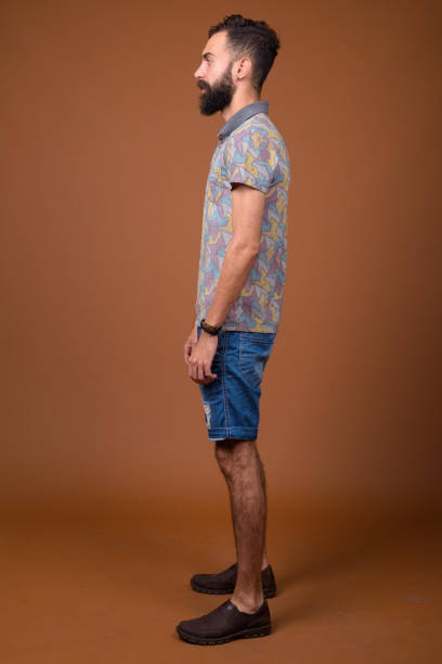 Studio shot of young handsome bearded Persian man against colored background