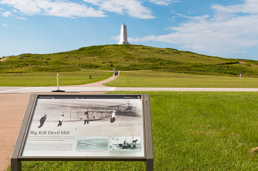 Kill Devil Hills, North Carolina - July 14, 2017:  Sign display for Big Kill Devil Hill with a granite memorial on top to commemorate the Wright Brothers at the Wright Brothers National Memorial.  The memorial recognizes the Wrights Brothers for the first successful flights in the early 1900s.  The tower was designed by Rodgers and Poor, a New York City architectural firm in 1932.