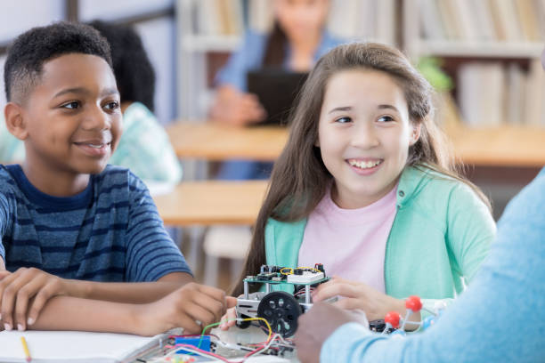 istock Two preteen students listen to teacher during robotics project 828329684