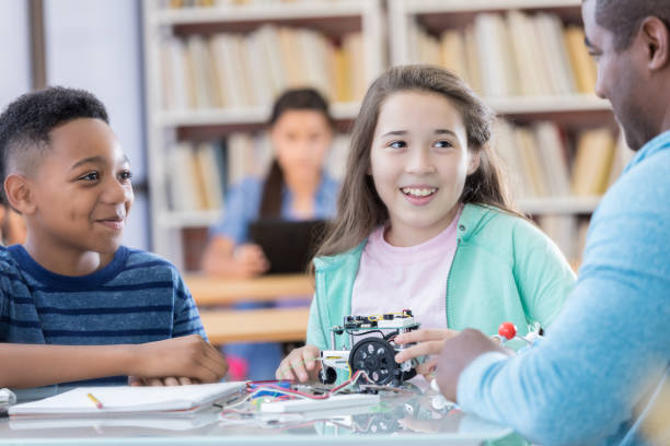 istock Two preteen students listen to teacher as they work on robotics project 828329932