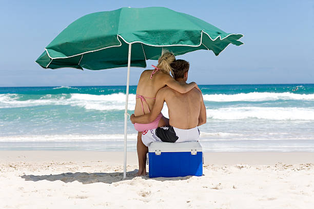 woman and man on a beach - male swimwear cooler 20s 뉴스 사진 이미지