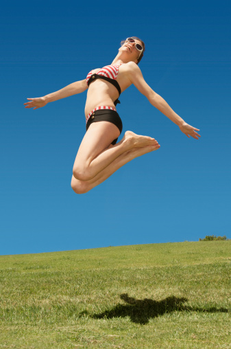 Blonde girl jumping in the air on white background.  some motion blur