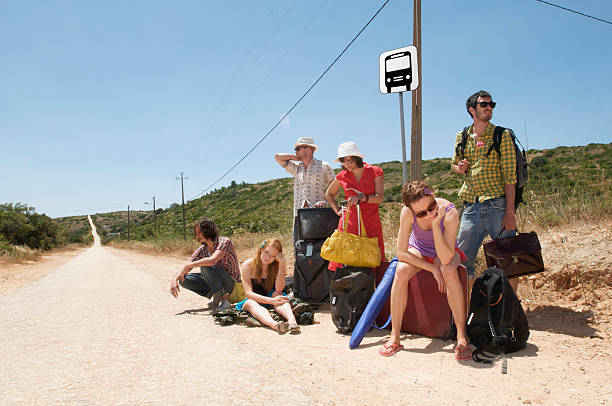 group waiting at a bus stop on long deserted road - stranded travel people traveling disappointment - fotografias e filmes do acervo