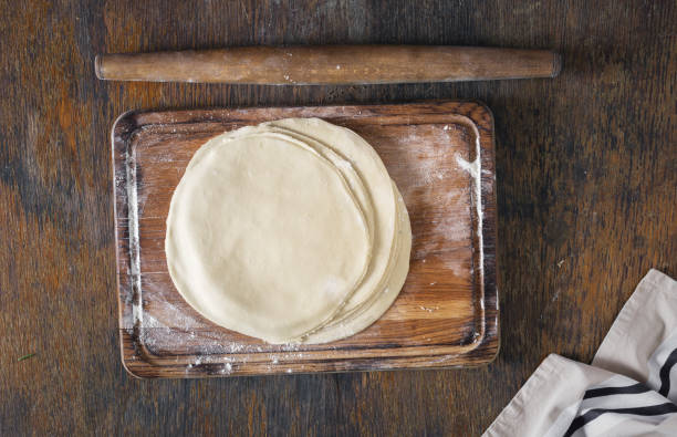 istock Raw tortillas on wooden board with rolling pin 828368480