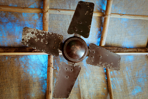 From below shot of metal and rusty propeller hanging under ceiling in tent.