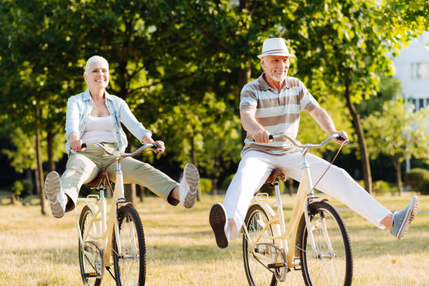 Joyful woman feeling happiness while cycling Like little children. Positive male person holding handle bar and keeping smile on his face while looking forward aging process stock pictures, royalty-free photos & images