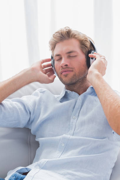 istock Man relaxing while listening to music on a couch 828376104