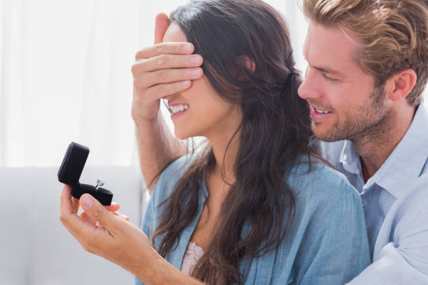 istock Man hiding his wifes eyes to offer her an engagement ring 828376638