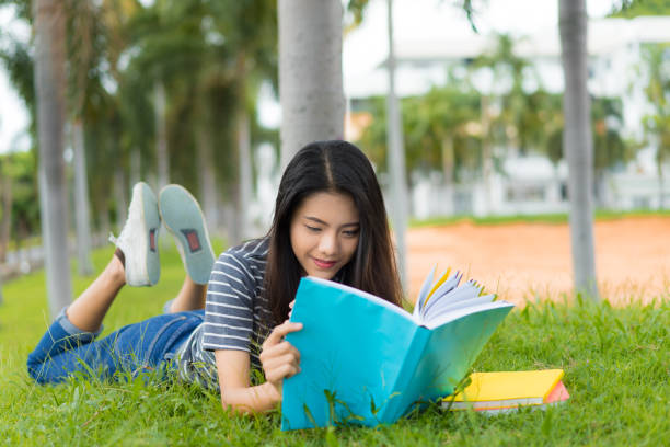 istock Asian young girl reading book relax on park 828403356