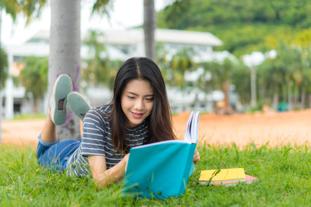 istock Asian young girl reading book relax on park 828403446