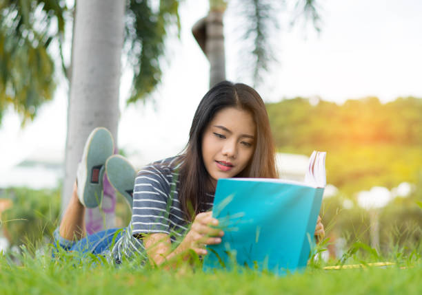 istock Asian young girl reading book relax on park 828403542