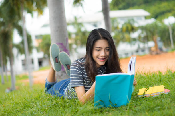istock Asian young girl reading book relax on park 828403638