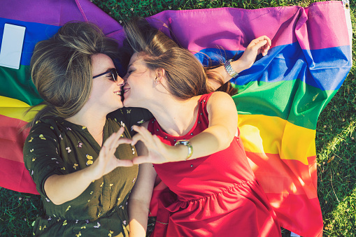 Lesbian couple with lgbt flag on grass