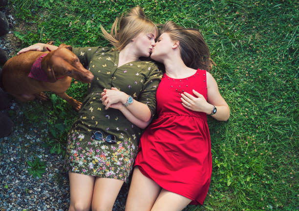Lesbian couple with dog lying on grass