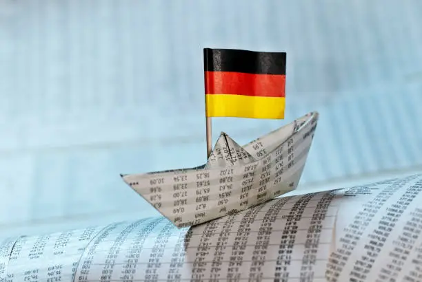 Paper ship with German flag on newspaper pages with course tables.